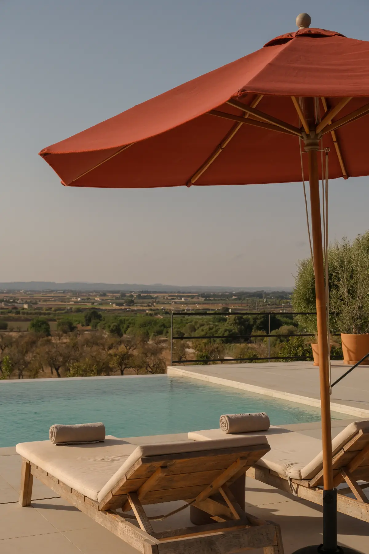 Sombrilla y hamacas junto a la piscina con vistas al campo